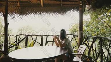 美丽的<strong>背景</strong>拍摄年轻快乐的<strong>旅游</strong>妇女享受早晨咖啡在惊人的热带森林<strong>酒店</strong>露台。